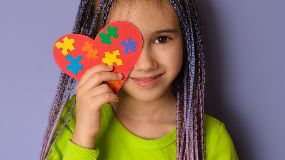 Girl holding a heart with puzzle pieces