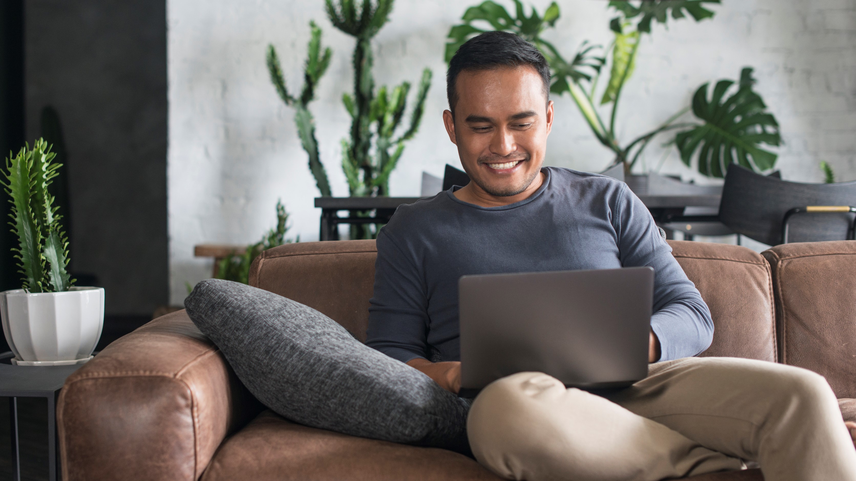 Young Asian man using the laptop in the living room.